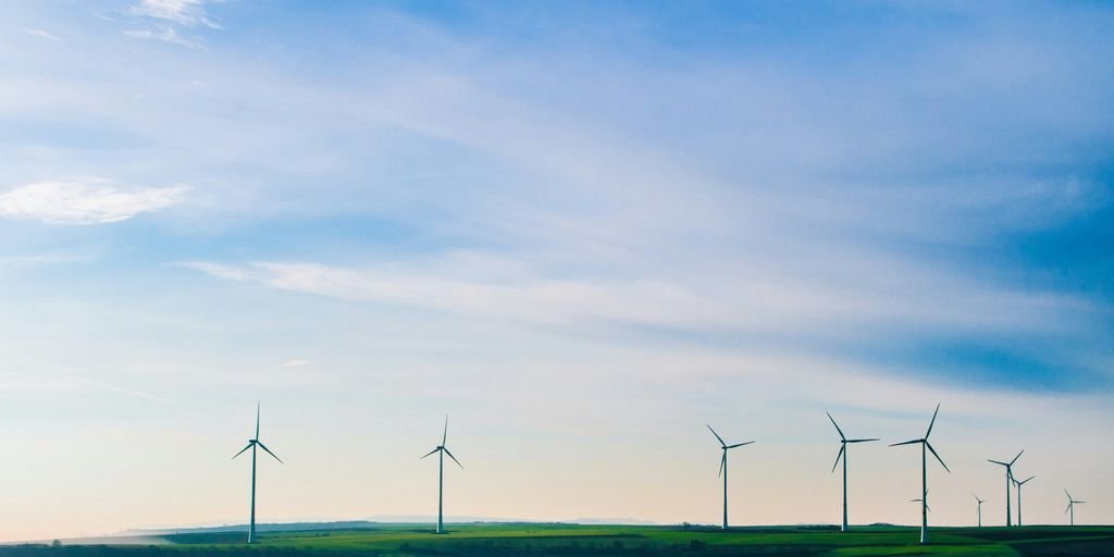 white windmills on green grass field under white clouds and blue sky