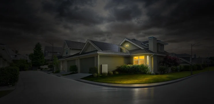 An aerial shot of a thunder storm, a blackout with one house having power, all the other houses look dark.